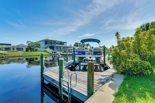 A dock with a boat, a house, and a grassy area.