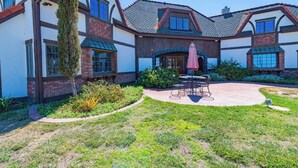 A two-story house with a patio, a dining table, and a pink umbrella.