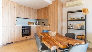 A modern kitchen with wooden cabinets, a built-in oven, and a dining area with a wooden table and chairs. - Apartment 'Vistamar 96' with Sea View, Wi-Fi and Air Conditioning (Benitachell)