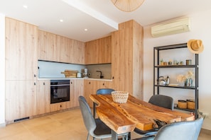 Una cucina moderna con mobili in legno, forno integrato e zona pranzo con tavolo e sedie in legno.