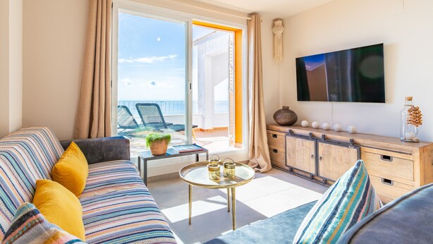 A modern living room with a sofa, a coffee table, and a TV on the wall. - Apartment 'Vistamar 96' with Sea View, Wi-Fi and Air Conditioning (Benitachell)