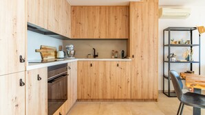 A modern kitchen with wooden cabinets, a built-in oven, and a dining area with a table and chairs. - Apartment 'Vistamar 96' with Sea View, Wi-Fi and Air Conditioning (Benitachell)