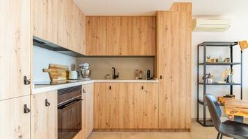 Una cocina moderna con armarios de madera, horno empotrado y comedor con mesa y sillas.