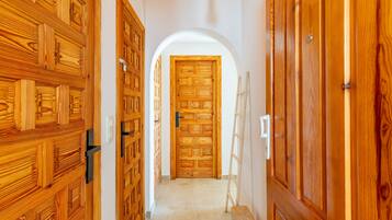 Un pasillo con puertas de madera y un arco blanco que da a una habitación.
