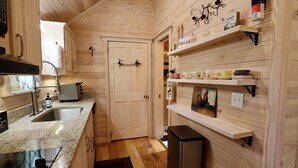 Una cocina compacta con paredes de madera, encimera de granito, pileta de acero inoxidable y horno integrado.