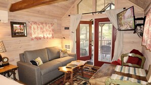 Un acogedor interior de cabaña con un sofá, una mesa de madera y un televisor montado en la pared.