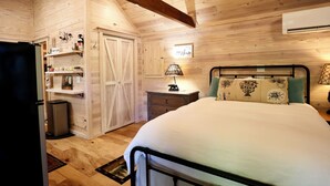 Un interior de madera con una cama, estantes, un refrigerador y un aire acondicionado.