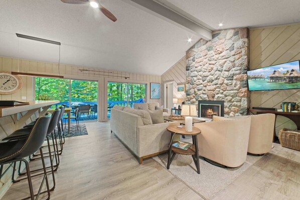 A modern living room with a stone wall, a fireplace, a TV, and a view of the outdoors.