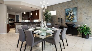 A modern dining area with a glass-top table, grey chairs, and a central decorative vase. - PGA West #41 3 BD/3 BA, 2,400 sf - 31+ Night Minimum Bookings Available (La Quinta)
