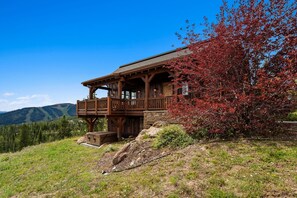 Une cabane en bois dotée d’un balcon, entourée d’un paysage montagneux.