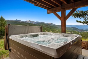 Un bain à remous doté d’une structure en bois et offrant une vue panoramique sur les montagnes.