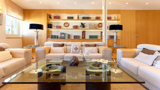 A modern living room with a glass coffee table, white sofas, and a wooden bookshelf with books and decorative items. - Exclusive Apartament in the Center. Tetuán III (Seville)