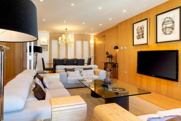 Una sala de estar moderna con un sofá, una mesa de centro y un televisor de pantalla plana montado en la pared.