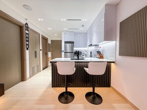 A modern kitchen with a central island, two bar stools, and a built-in oven.