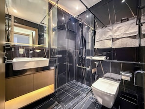 A modern bathroom with a glass-enclosed shower, a white sink, and a toilet.