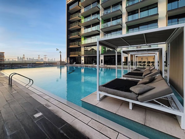 A rooftop pool with lounge chairs and a view of the city skyline.