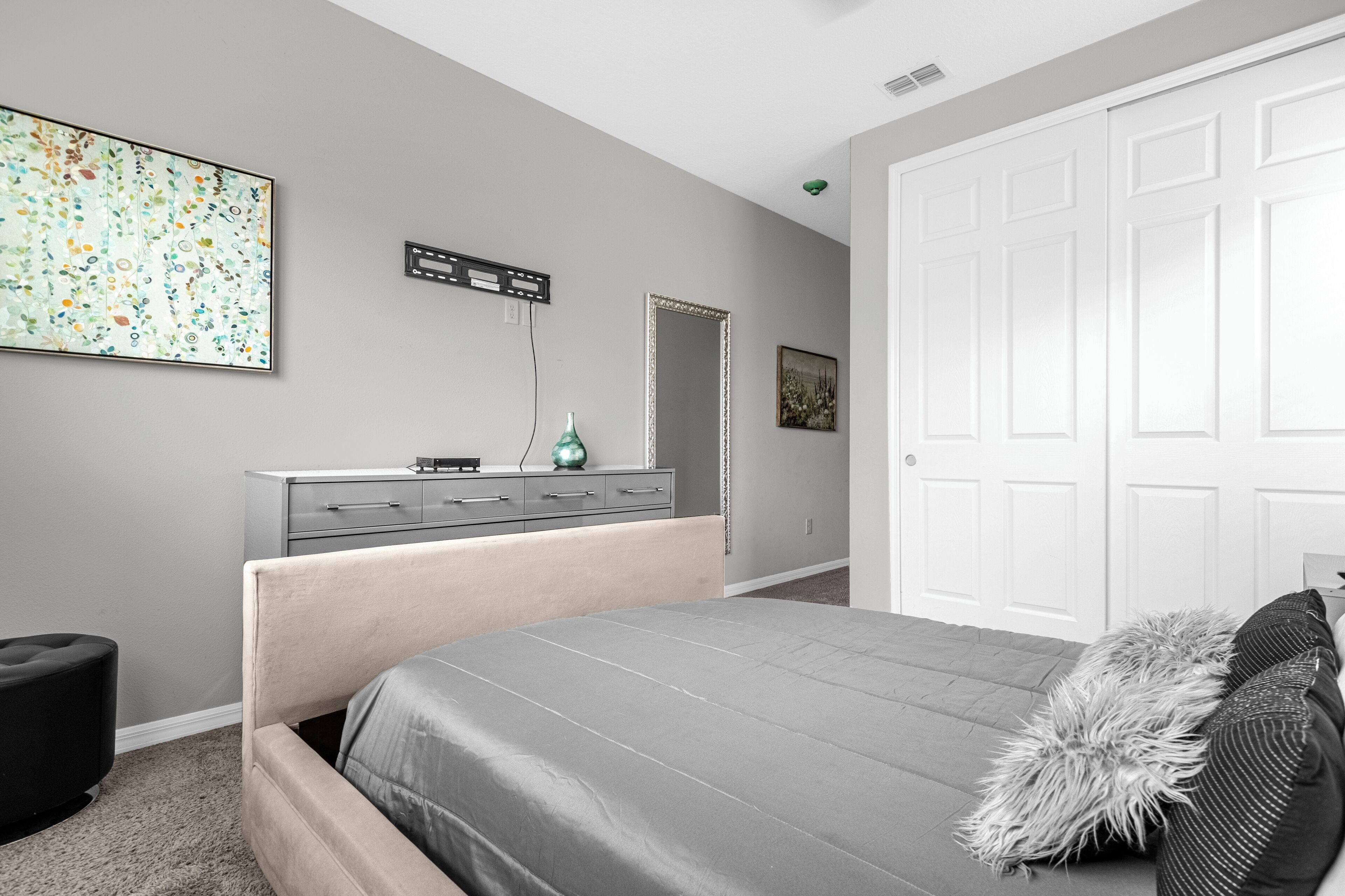Un dormitorio con cama, cómoda, espejo y obras de arte en la pared.