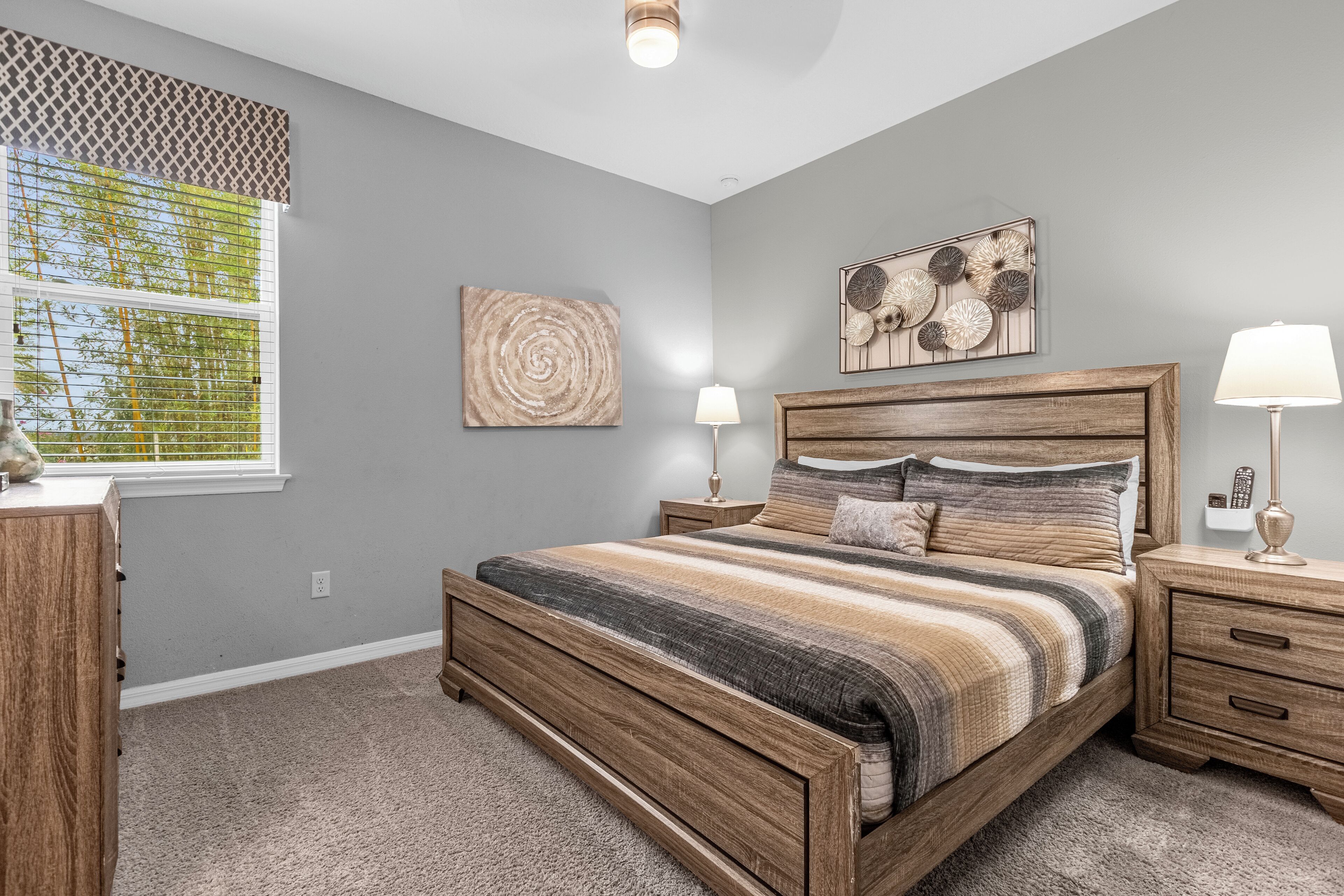 Un dormitorio con cama de madera, dos mesitas de noche con lámparas, una ventana con persianas y decoración en la pared.