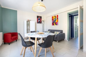Un coin repas avec une table ronde, des chaises noires, un canapé rouge et un meuble blanc.