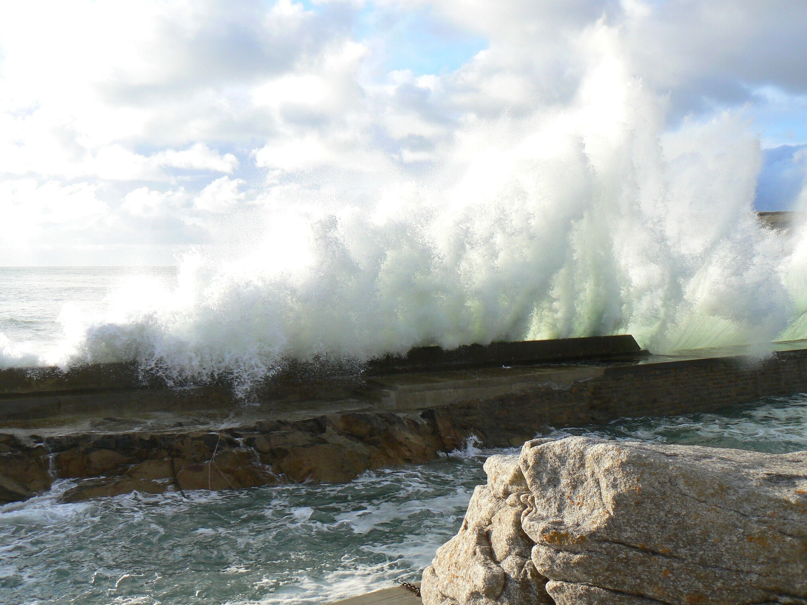 A coastal scene with waves crashing against a stone structure.
