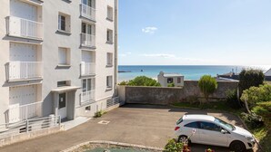 Un edificio a più piani con balconi, un'area di parcheggio e vista sul mare.