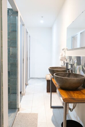 A modern bathroom with a large stone basin, a wooden vanity, and a glass shower enclosure. - Modular Dreams Hostel (Madrid)