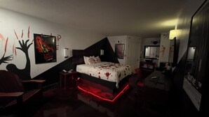 A bedroom with a bed, a chair, a desk, and a mirror. - Special boutique hotel in Oxford, Alabama with a variety of themed rooms! (Oxford)