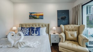 Een hotelkamer met een bed, een stoel, een nachtkastje, een lamp en kunst aan de muur.
