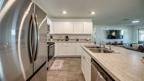 A modern kitchen with white cabinets, stainless steel appliances, and a large island with a sink.