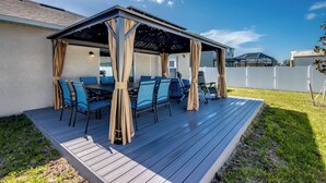 An outdoor patio with a covered seating area, a table, and chairs.