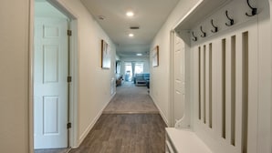 A hallway with a wooden floor, white walls, and a white door at the end.