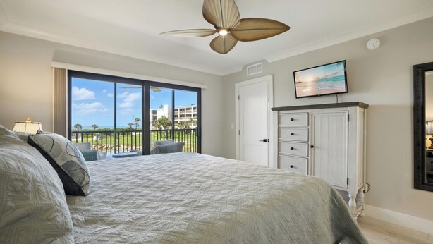 A bedroom with a large bed, a ceiling fan, a TV, and a view of the outdoors. - 🌺Sand Pointe 214- All New Luxury with Sweeping Gulf Views *POOL NOT OPEN🐬 (Sanibel)