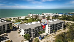 A multi-story hotel with a rooftop pool, located near a beach with clear skies. - 🌺Sand Pointe 214- All New Luxury with Sweeping Gulf Views *POOL NOT OPEN🐬 (Sanibel)