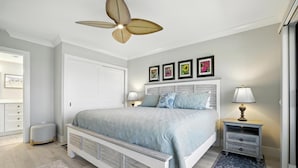 A bedroom with a bed, bedside tables, a ceiling fan, and a wall-mounted TV. - 🌺Sand Pointe 214- All New Luxury with Sweeping Gulf Views *POOL NOT OPEN🐬 (Sanibel)