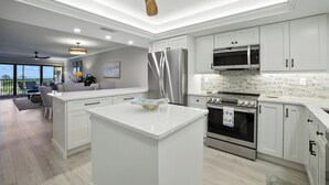 A modern kitchen with white cabinetry, stainless steel appliances, and a central island. - 🌺Sand Pointe 214- All New Luxury with Sweeping Gulf Views *POOL NOT OPEN🐬 (Sanibel)
