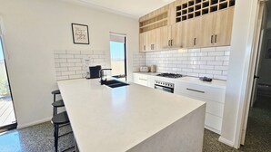 Una cocina moderna con una isla grande, armarios blancos y vistas al exterior.