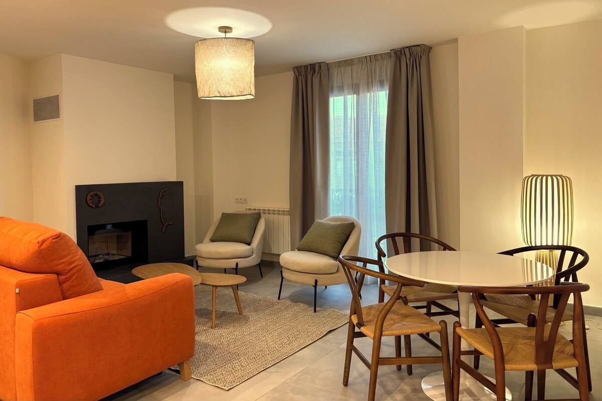 A modern living room with a sofa, chairs, a dining table, and a fireplace.