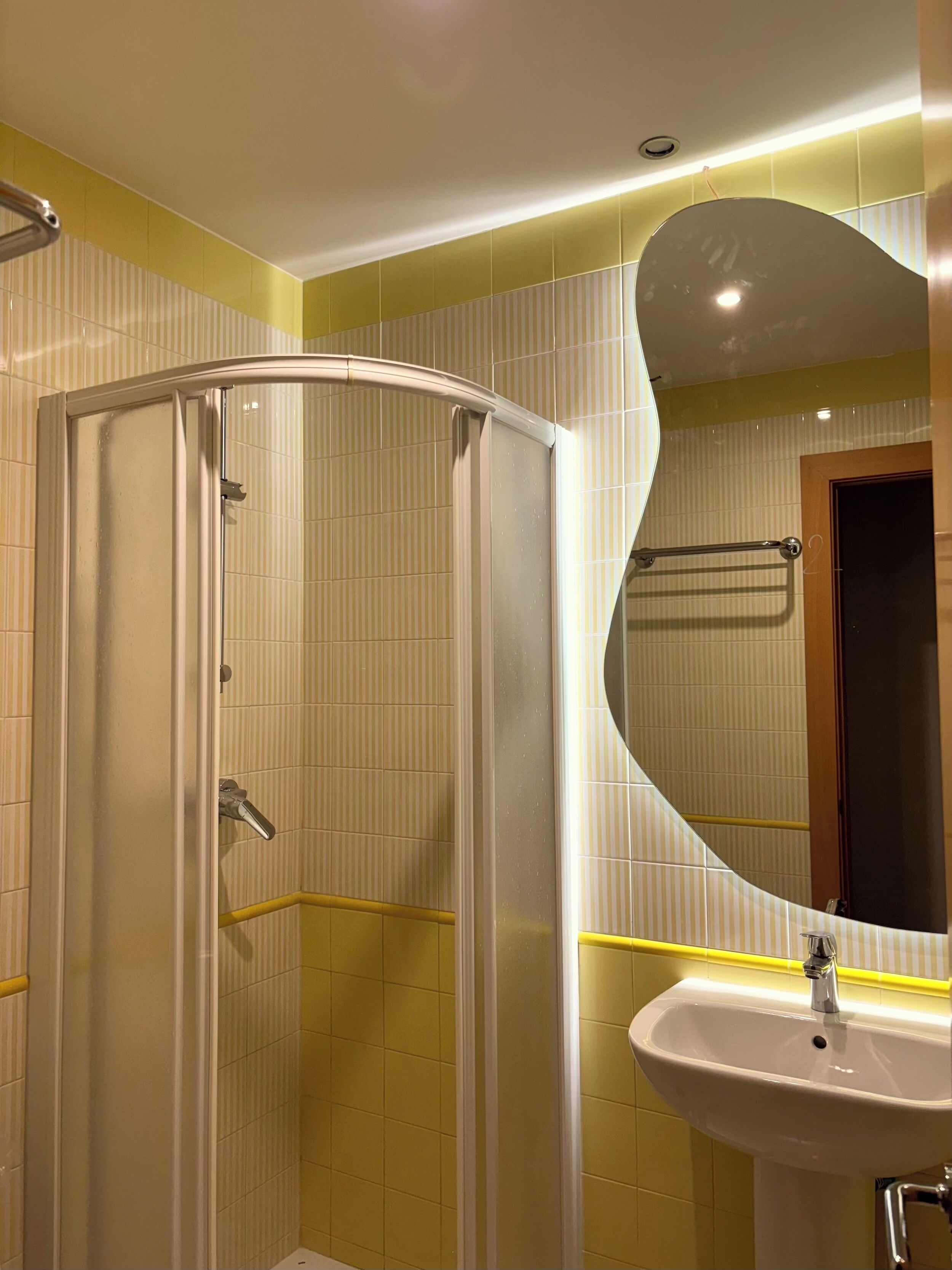 Un baño con cabina de ducha, lavabo y espejo.