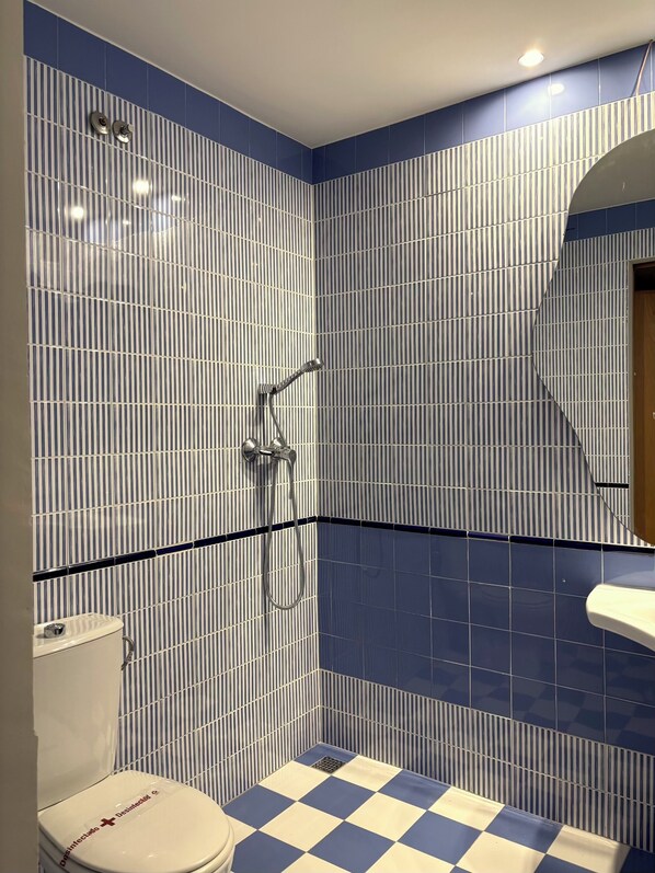 A bathroom with a checkered floor, a toilet, and a shower area with striped tiles.