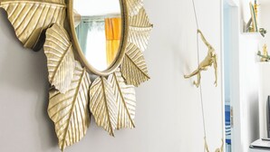 A wall-mounted gold leaf mirror with a reflection of a room. - Cozy, Spacious condo with balcony and beautiful serene mountain views. (Cluses)