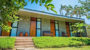 A modern building with a concrete facade, large windows, and a small outdoor seating area with steps leading to the entrance. - Pousada Casa do Pescador Camburi (São Sebastião)