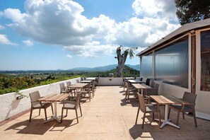 Patio esterno con tavoli e sedie, affacciato su un paesaggio suggestivo.