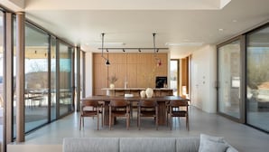 A modern kitchen with a wooden countertop, a dining area with a large table and chairs, and large sliding glass doors. - Villa bOX by Villas Guide (Brajkovici)