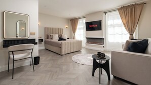 Ein modernes Hotelzimmer mit einem großen Bett, einer Couch, einem Fernseher und einem Kamin.