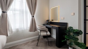 Une chambre moderne avec une grande fenêtre, un bureau doté d’un miroir, une chaise et une plante en pot.
