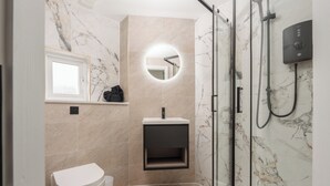 Une salle de bain moderne équipée de toilettes, d’un lavabo et d’un espace douche.