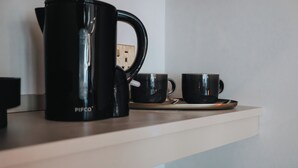 A kitchen counter with a black coffee maker, two black mugs, and a white shelf. - Bold St | King Room | Fireplace | Private Ensuite (Liverpool)
