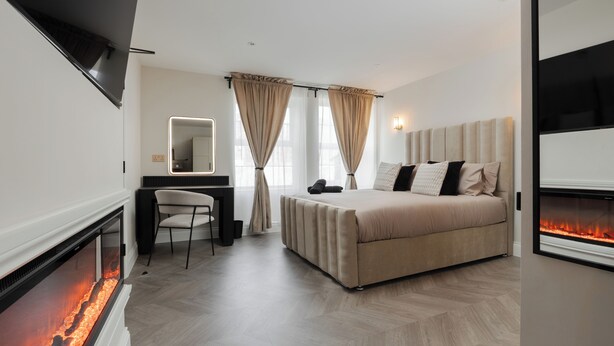 A modern bedroom with a bed, a desk, a chair, and a fireplace. - Bold St | King Room | Fireplace | Private Ensuite (Liverpool)