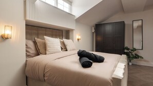 A bedroom with a large bed, a dark wardrobe, a potted plant, and a skylight. - Bold St | Skylight Charm with Fireplace | King Bed (Liverpool)