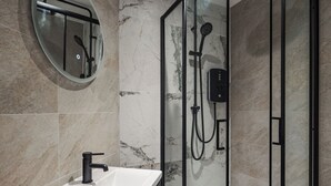 A modern bathroom with a glass-enclosed shower, a round mirror, and a white sink. - Bold St | Football & Nightlife | Centre City Stay (Liverpool)